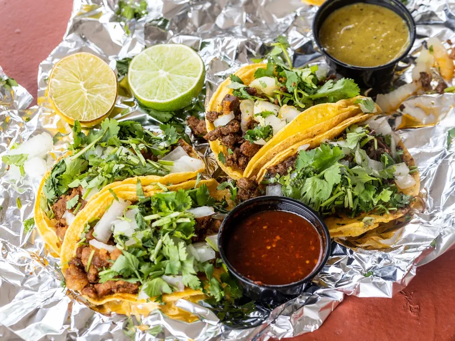 Al pastor street tacos in foil with lime and two salsas
