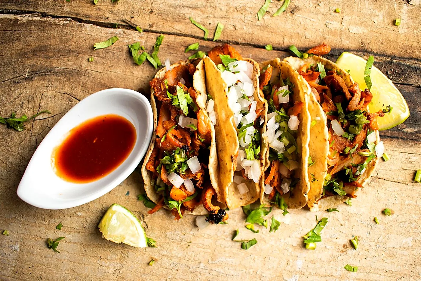Three chicharrón street tacos — pork simmered soft in salsa, with onion, cilantro and lime