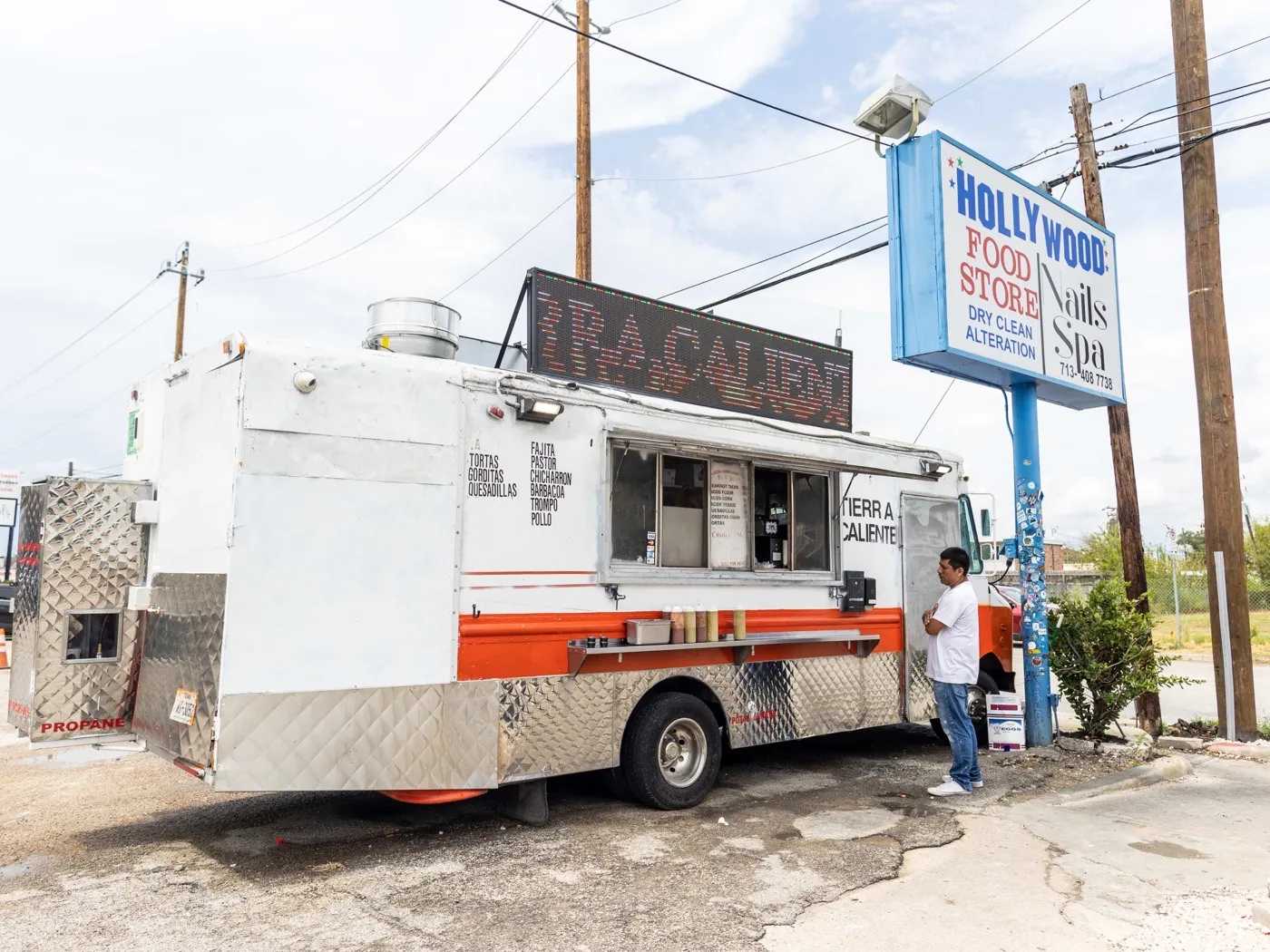 The white-and-orange Tacos Tierra Caliente truck parked on West Alabama Street in Montrose, with a customer at the window